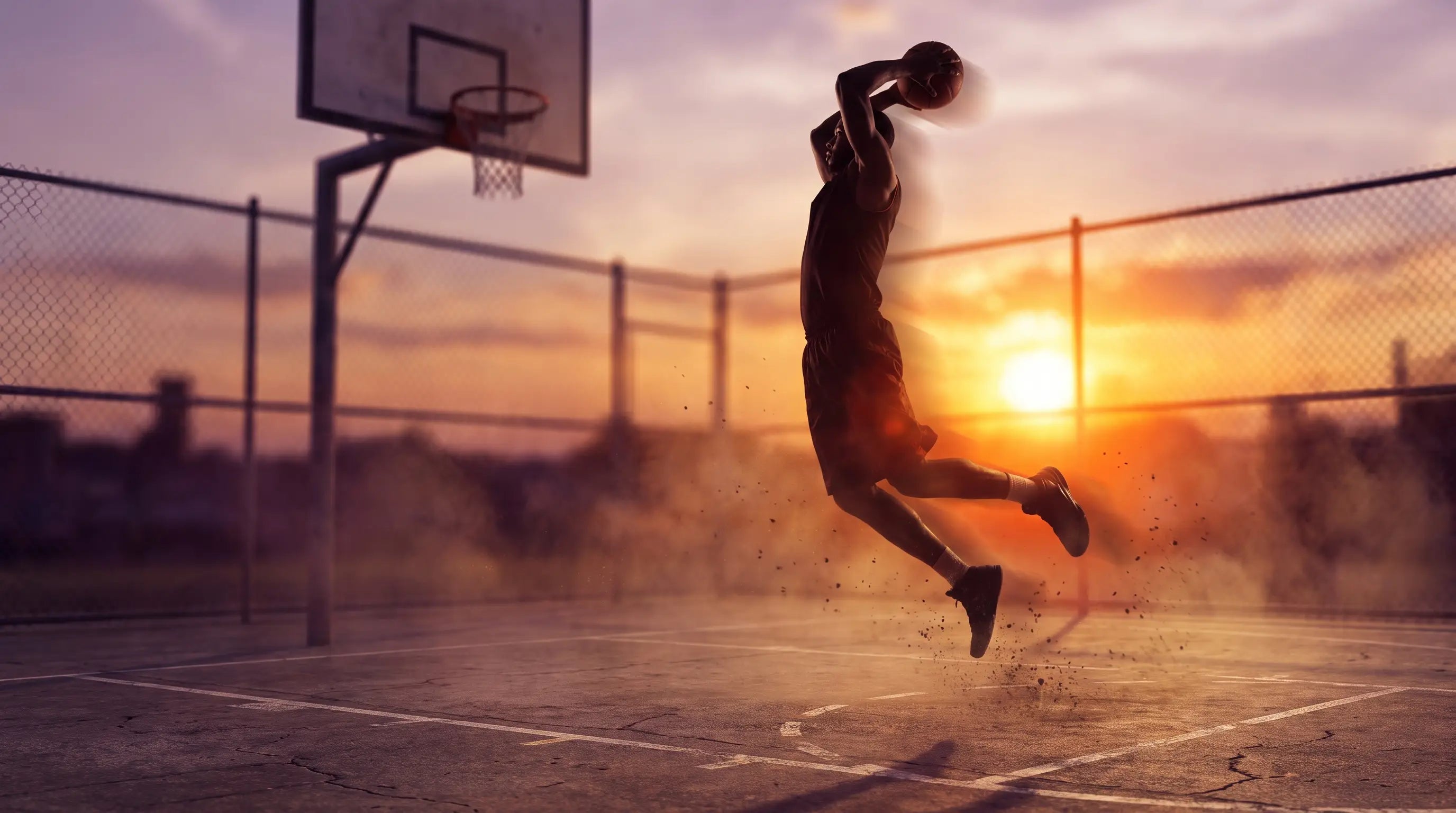 Basketball player rising for a dunk at sunset
